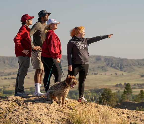 Four hikers and a dog overlooking a rugged landscape