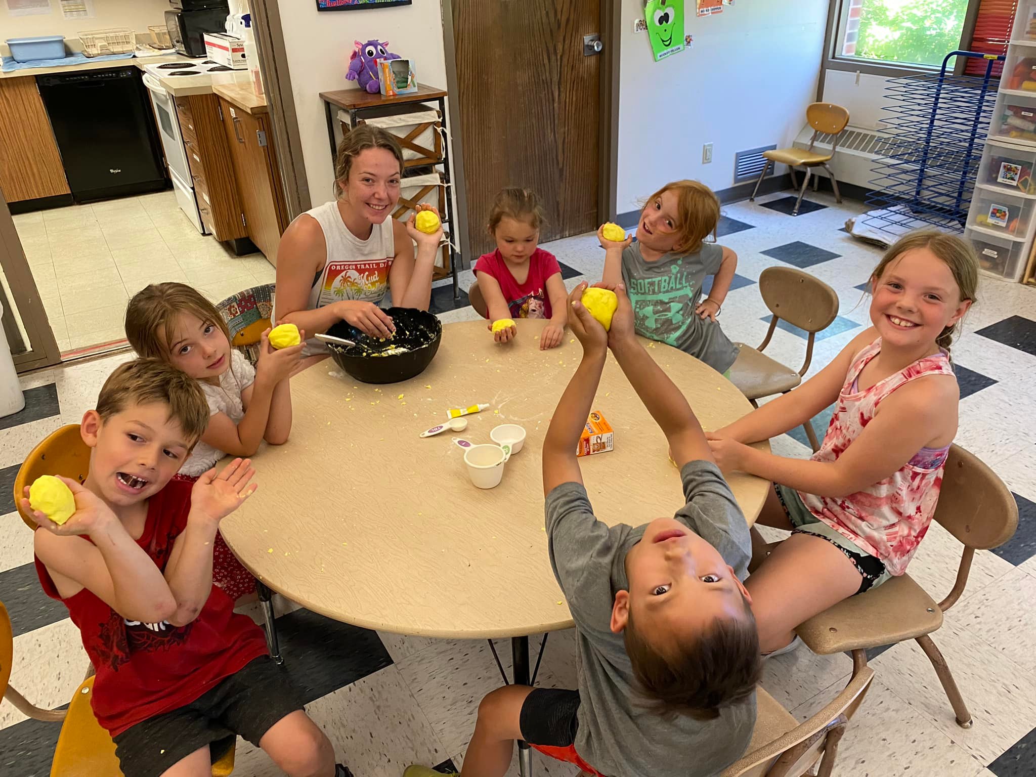 A group of children and a student volunteer smile at the Child Development Center