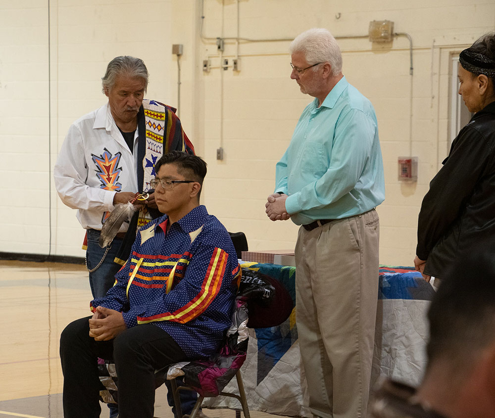 Steve Dubray, medicine man and uncle of Vernon Plenty Bull, left, explains the eagle feather-tying ceremony. Mark Hunt, CSC Security Supervisor and Plenty Bull's work supervisor, right, during the ceremony April 28, in Armstrong Gymnasium.