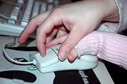 Closeup of an adult hand helping a child's hand click a mouse