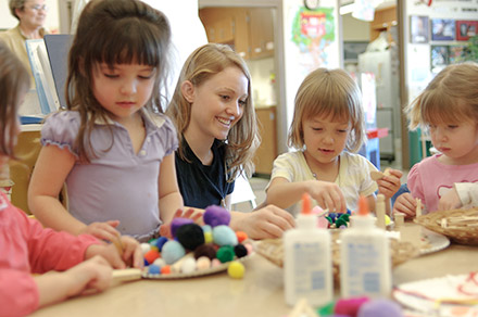 A student volunteer works with children on an art project at the Child Development Center Laboratory