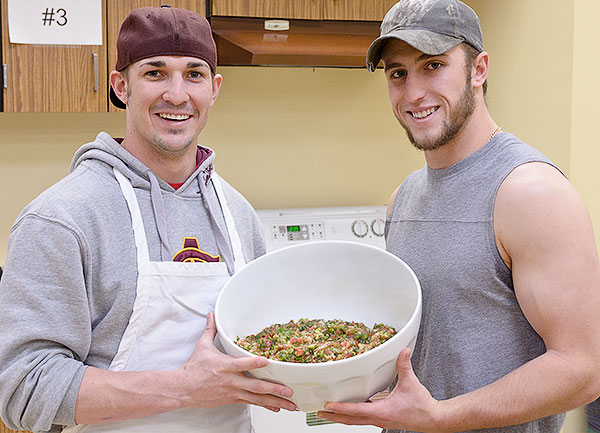 Two students hold a bowl of salsa they prepared