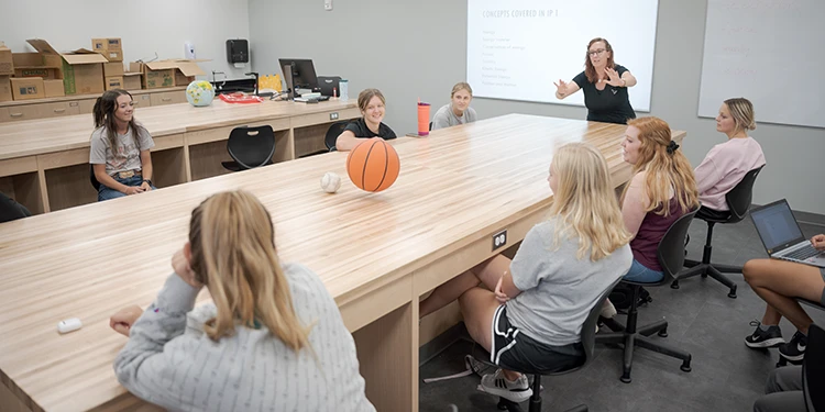 A teacher using a basketball to demonstrate motion to high school age students