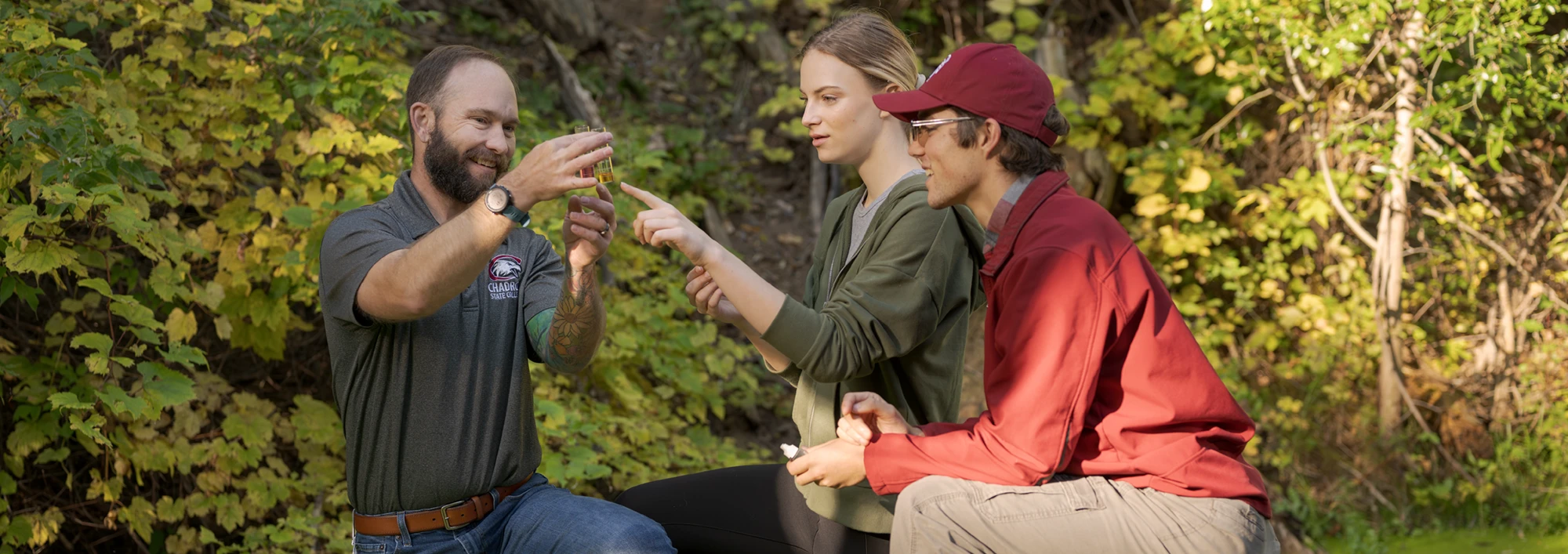 A rangeland professor and two students examing a water sample during a field trip