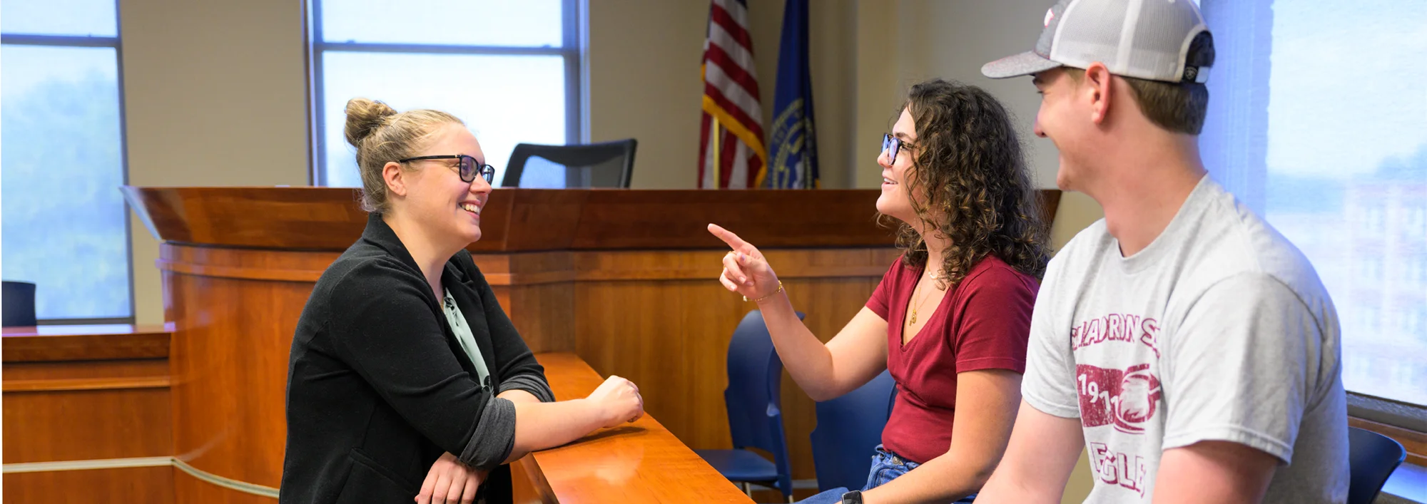Two students speaking to a legal studies professor in a classroom set up as a mock courtroom