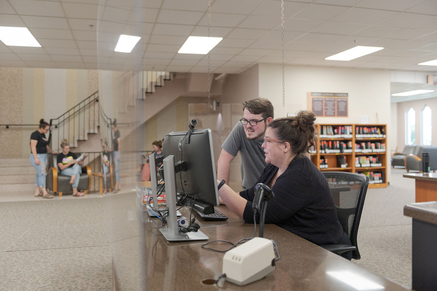 A staff member and student review a database at the King Library