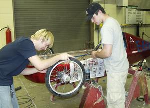 Students Kory Westers and Kyle Demaree work on the electrice vehicle's brakes.