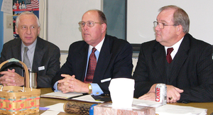 Three men sitting at a table discuss education with students