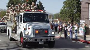 Members of the 1057th ride by firetruck past Chadron State College on Monday.