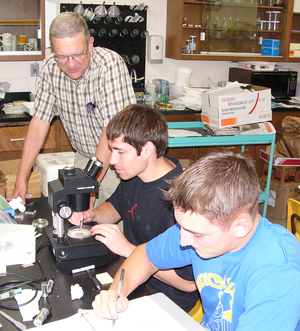 Professor Randy Lawson looks on while Justin Schwarting used a microscope to sort mosquitoes and Adam Wells records data.