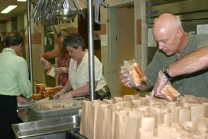 Tim Anderson bags meals for firefighters while CSC employees Connie Rasmussen and Loree MacNeill make sandwiches.