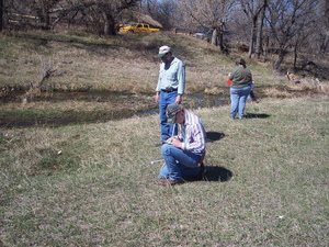 Chadron State student Justin Lemmer, kneeling, is assisted by range science professor Dr. Chuck Butterfield in carrying out a vegetation survey near Chadron Creek while Kim Davis observes riparian vegetation.