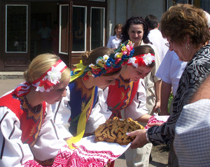 CSC Dean Dr. Margaret Crouse is greeted with a plate of ornate bread by three Ukrainian girls.