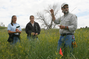 Chuck Butterfield talks to students in a field