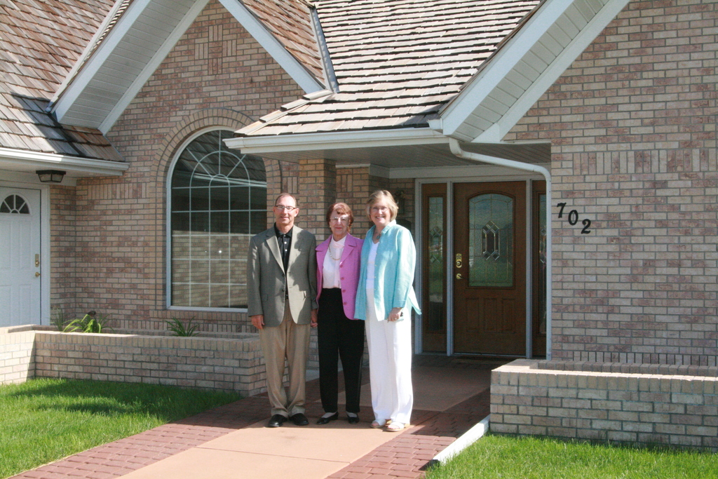 Randy Bauer and Janie Park stand with Madge Fortune Chicoine at the entrance of the house that is being donated to the college.