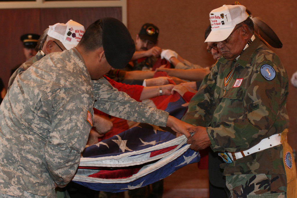 Mervin Garneaux, at left, and Vincent Ten Fingers join others in presenting one of the three flags that were flying at the World Trade Center on 9/11.