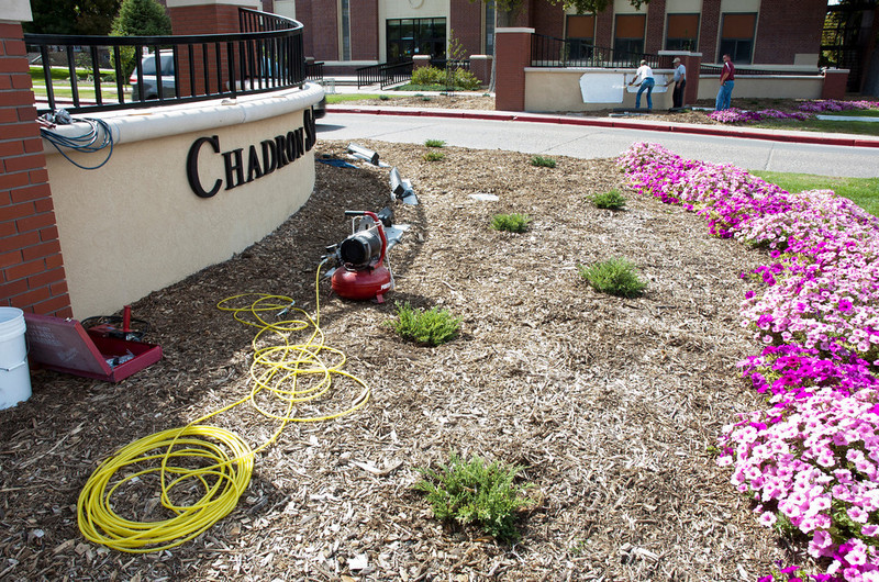 Workers lay out the lettering and artwork of the new campus entrance portal.