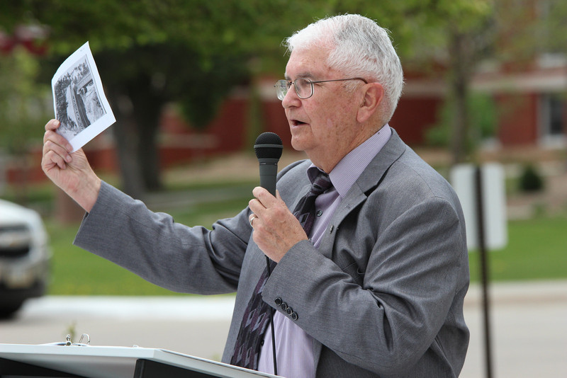 Longtime Chadron State College newsman Con Marshall displays a photo from the archives during his keynote presentation of the Centennial Time Capsule Dedication Ceremony on April 26. The photo portrays an accident by a truck of the Buckingham Freightlines, the company started by an enterprising family with strong CSC ties. (Photo by Justin Haag)