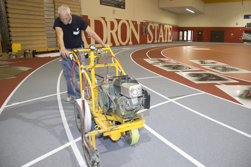 David Spellman pushes the striping machine in Chadron State College's Nelson Physical Activity Center on Wednesday. The arena, with its new synthetic flooring, will be open to the public Monday. (Photo by Justin Haag)