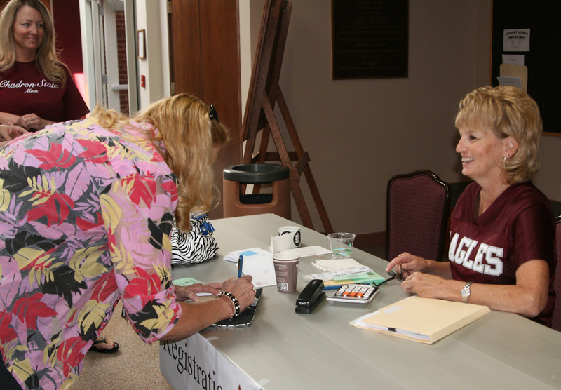 Chadron State College office assistant Kathy Mason, at right, registers Family Day visitors last year in the Student Center. (Photo by Justin Haag)