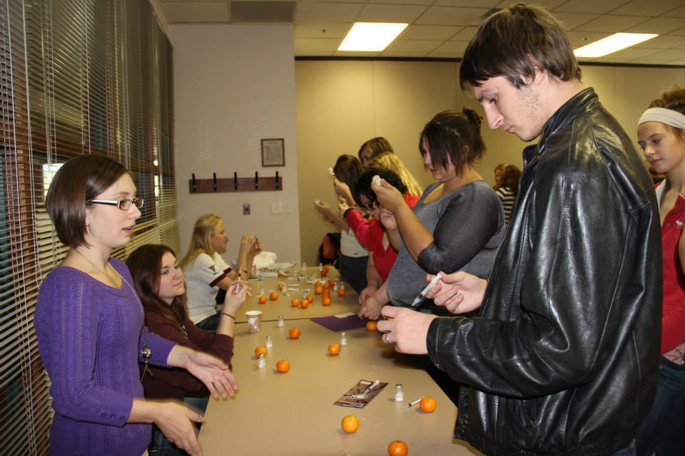 Chadron State College freshman Kayla Daniels assists Henry Schuff of Garden County High School at one of many hands-on modules during the 2013 Health Professions Showcase. (Tena L. Cook/Chadron State College)