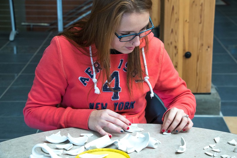 Carson Hadden pieces together a broken pottery item