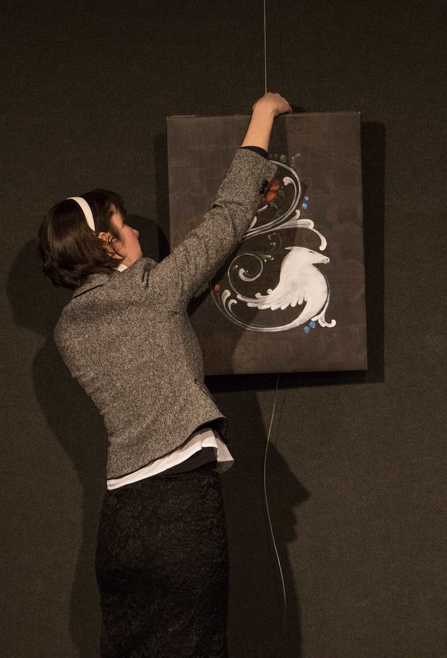 Carly Heath hangs White Horse Rosemaling, a digital illustration on canvas, for the Chadron State College art faculty show, 