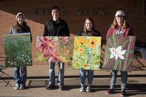 Four art students pose with their wildflower paintings