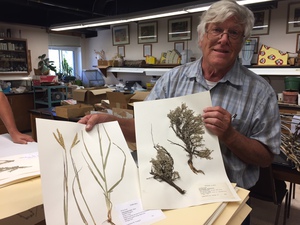 Larry Young poses with two plant specimen samples