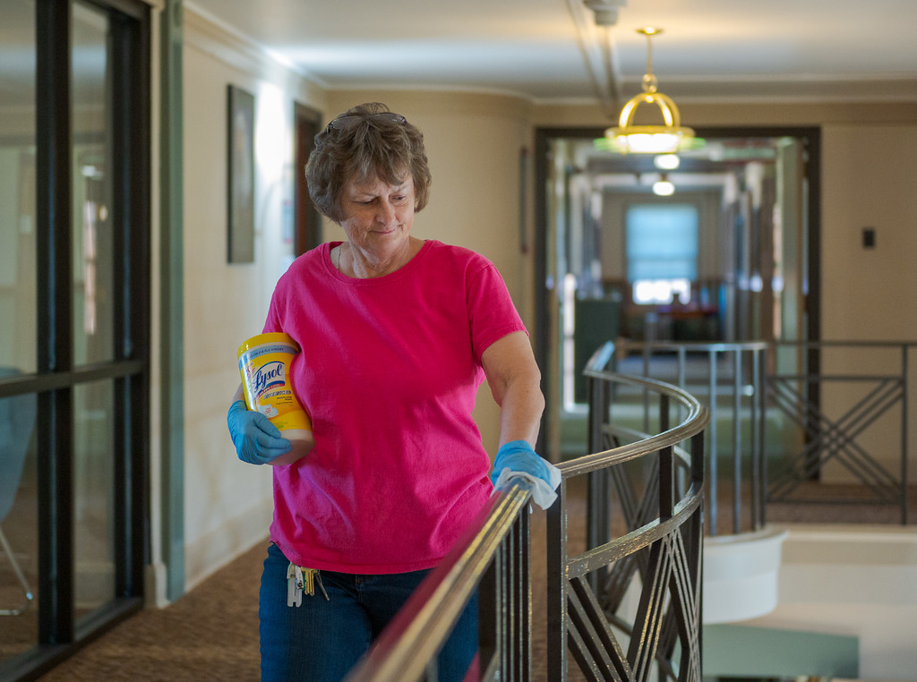 Custodian Rose Fankhauser wipes down the balcony railing in the main lobby at Crites Hall.