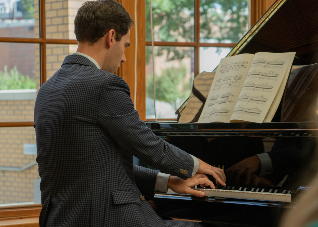 Dr. Brooks Hafey performs a piano solo in the Sandoz Center Chicoine Atrium