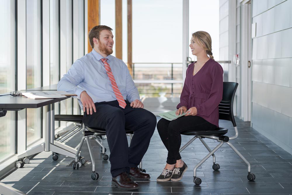 Two faculty members sit discussing with each other on the CSC Campus.