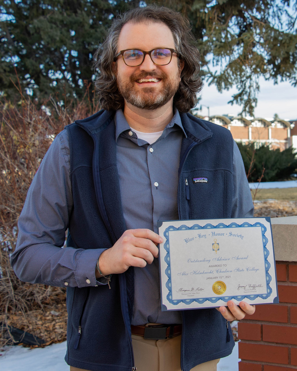 Alex Helmbrecht stands holding his national Blue Key award.