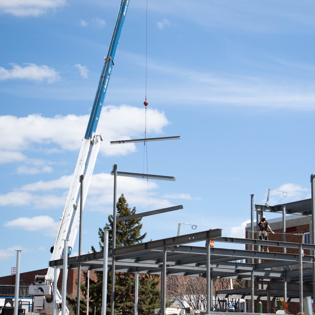 Three steel beams are lowered to Chadron State College's Math Science Center