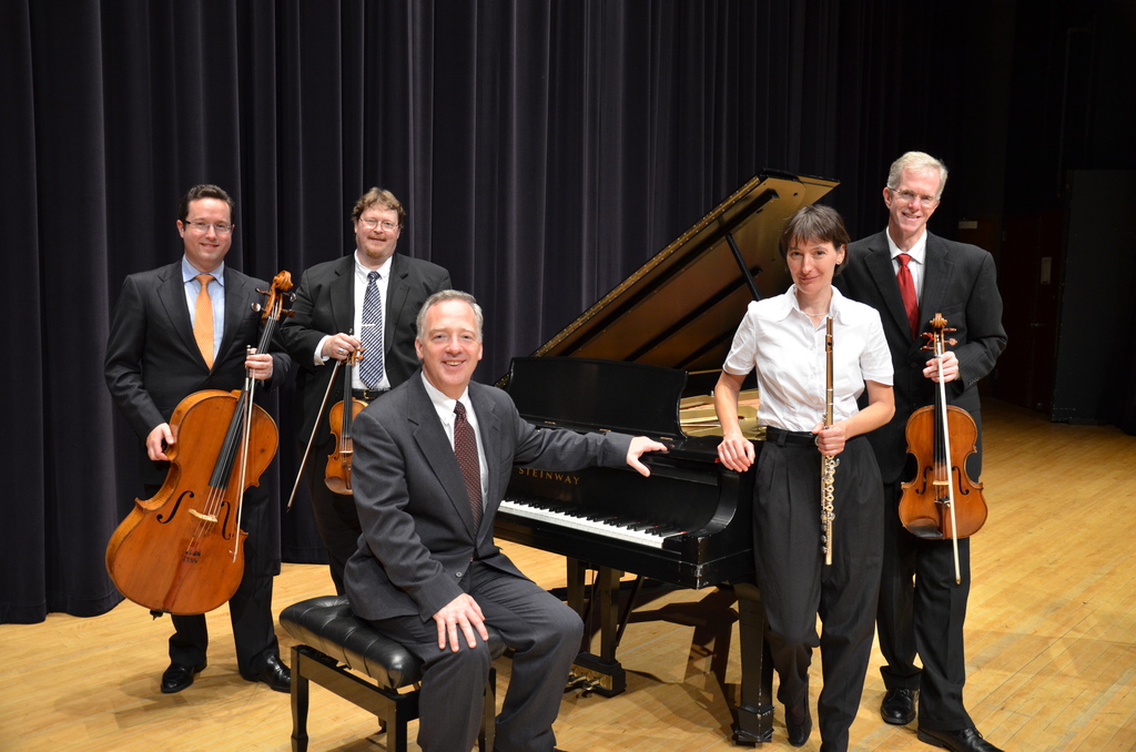 The Trans Nebraska Players quintet posed at a piano holding their instruments.