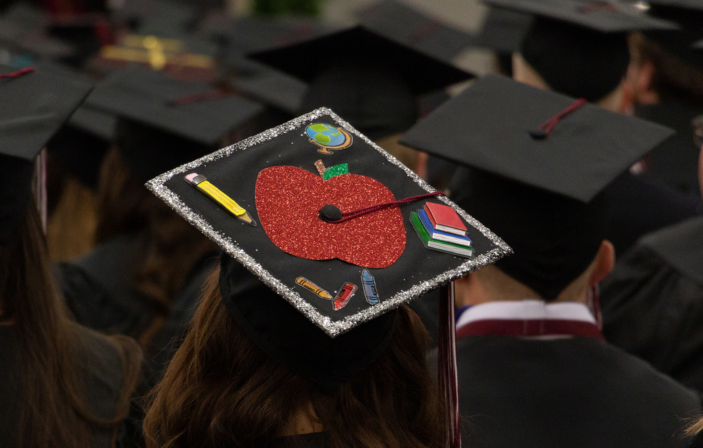 A girls graduation cap with apple on it.