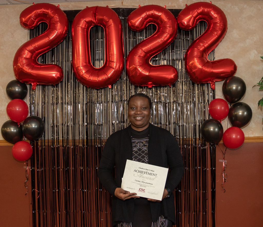 Health professions student holds award in front of backdrop.