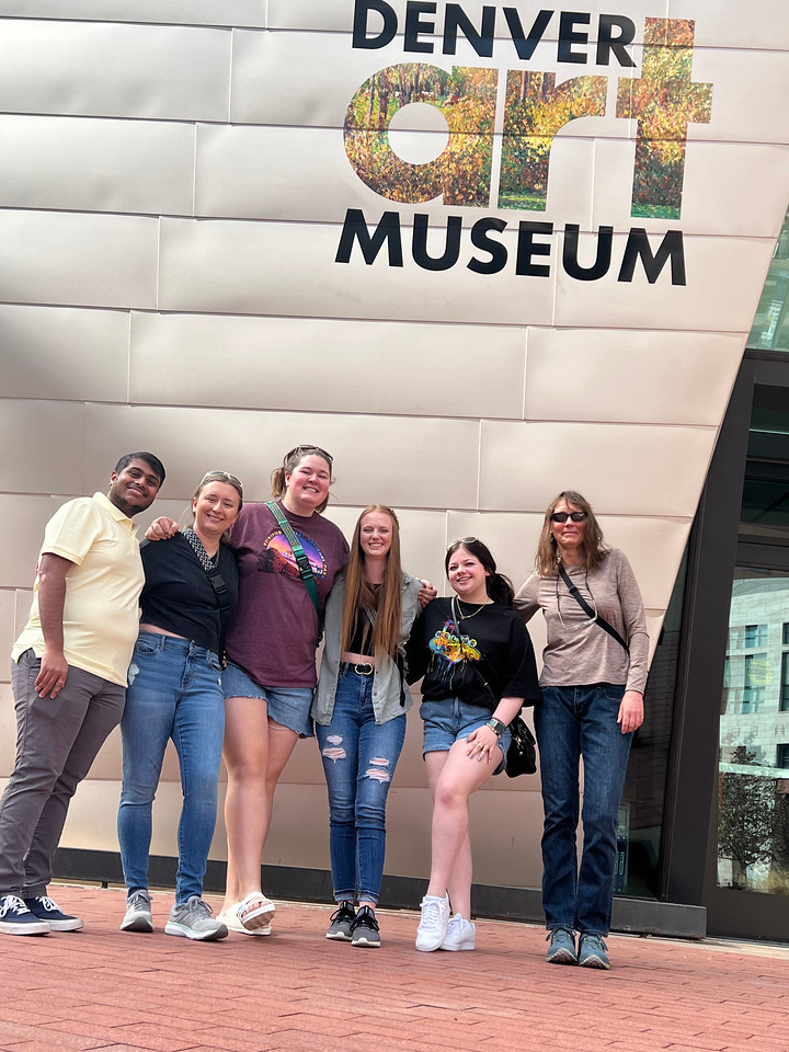 Five students and one staff member pose outside of Denver Art Museum.