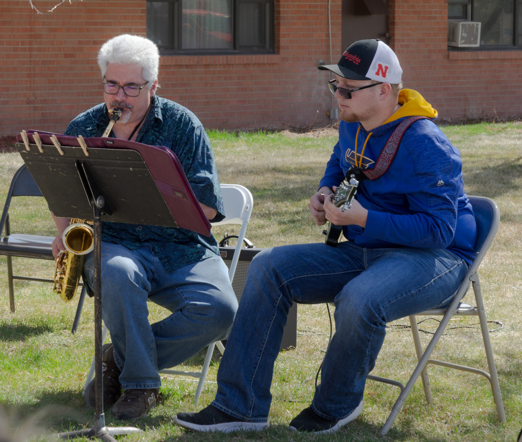 Two band members sit playing their instruments