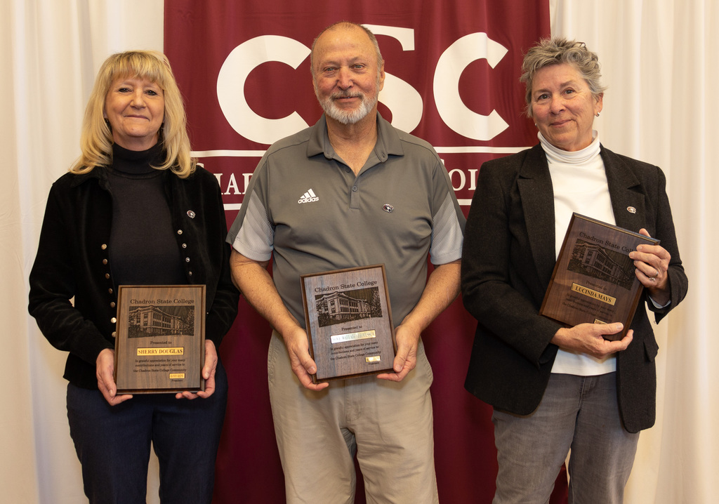 Three CSC Staff members stand holding a plaque earned for their retirement.