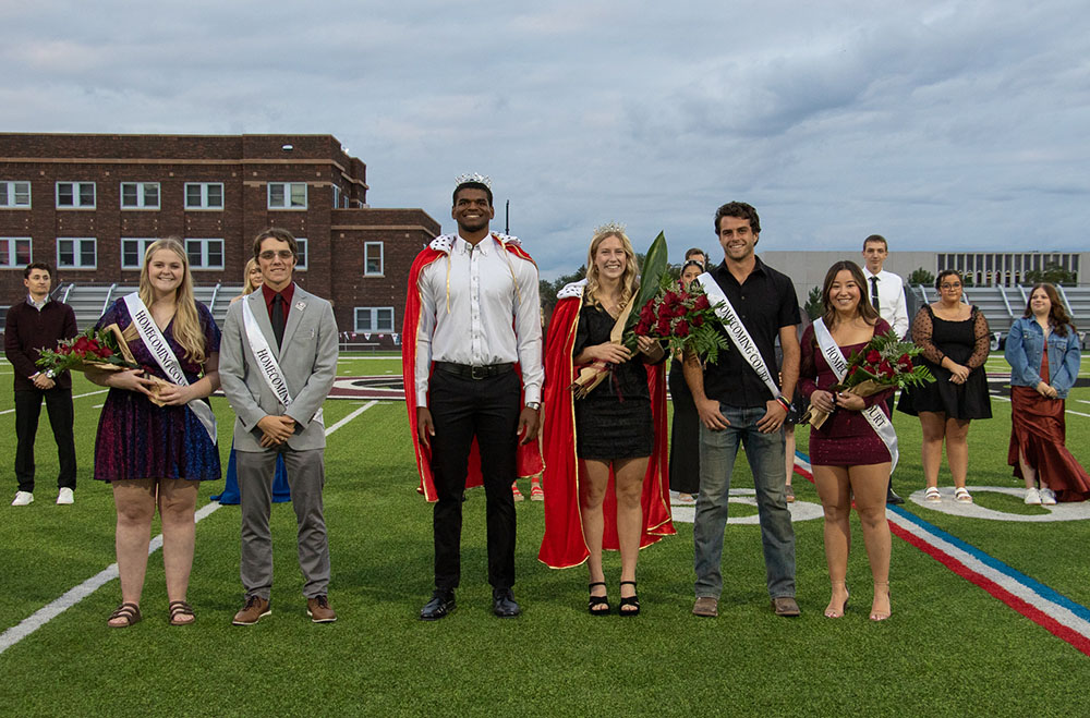 Six adults standing on a football field