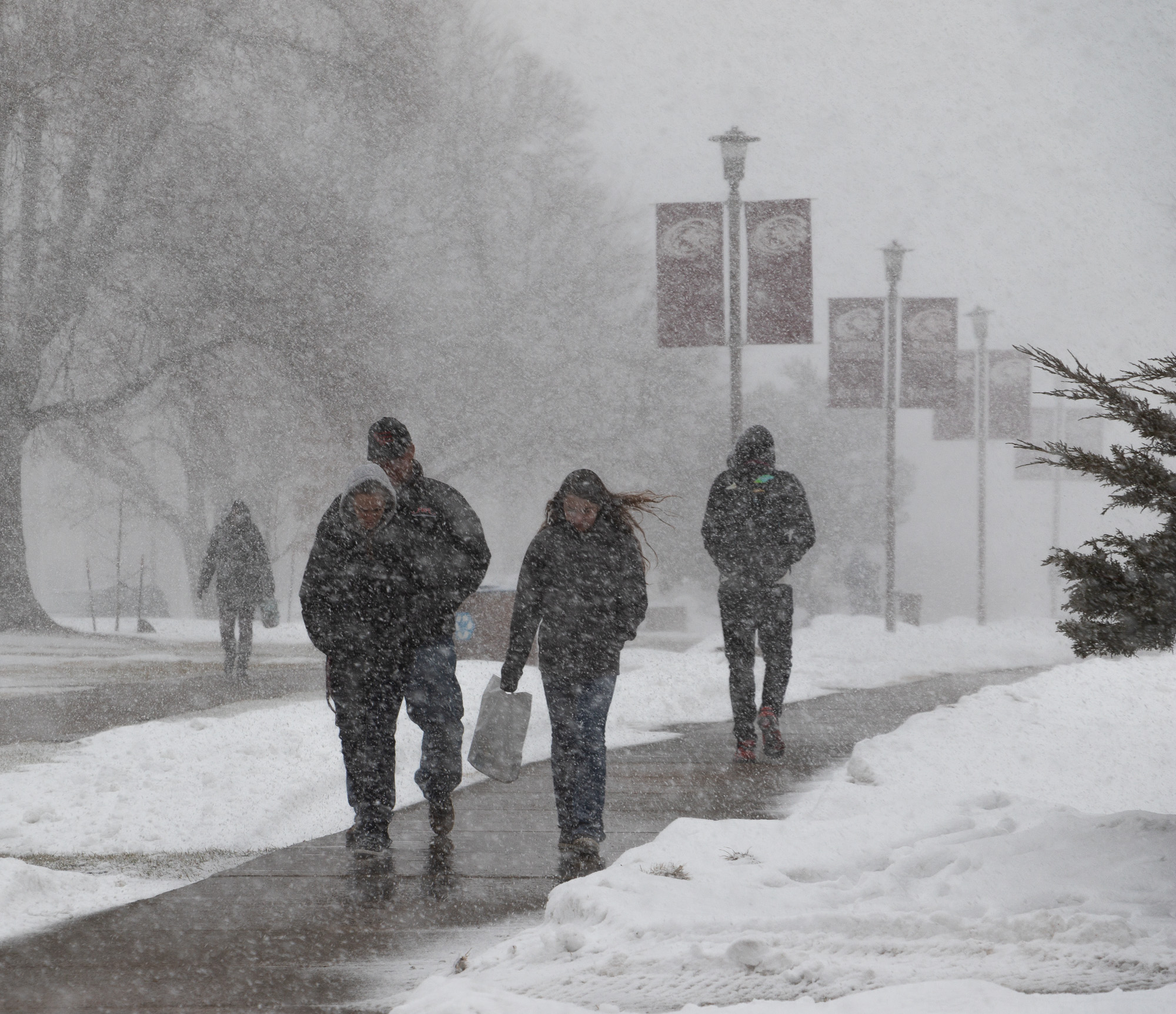 Students walk the sidewalk during a snowstorm