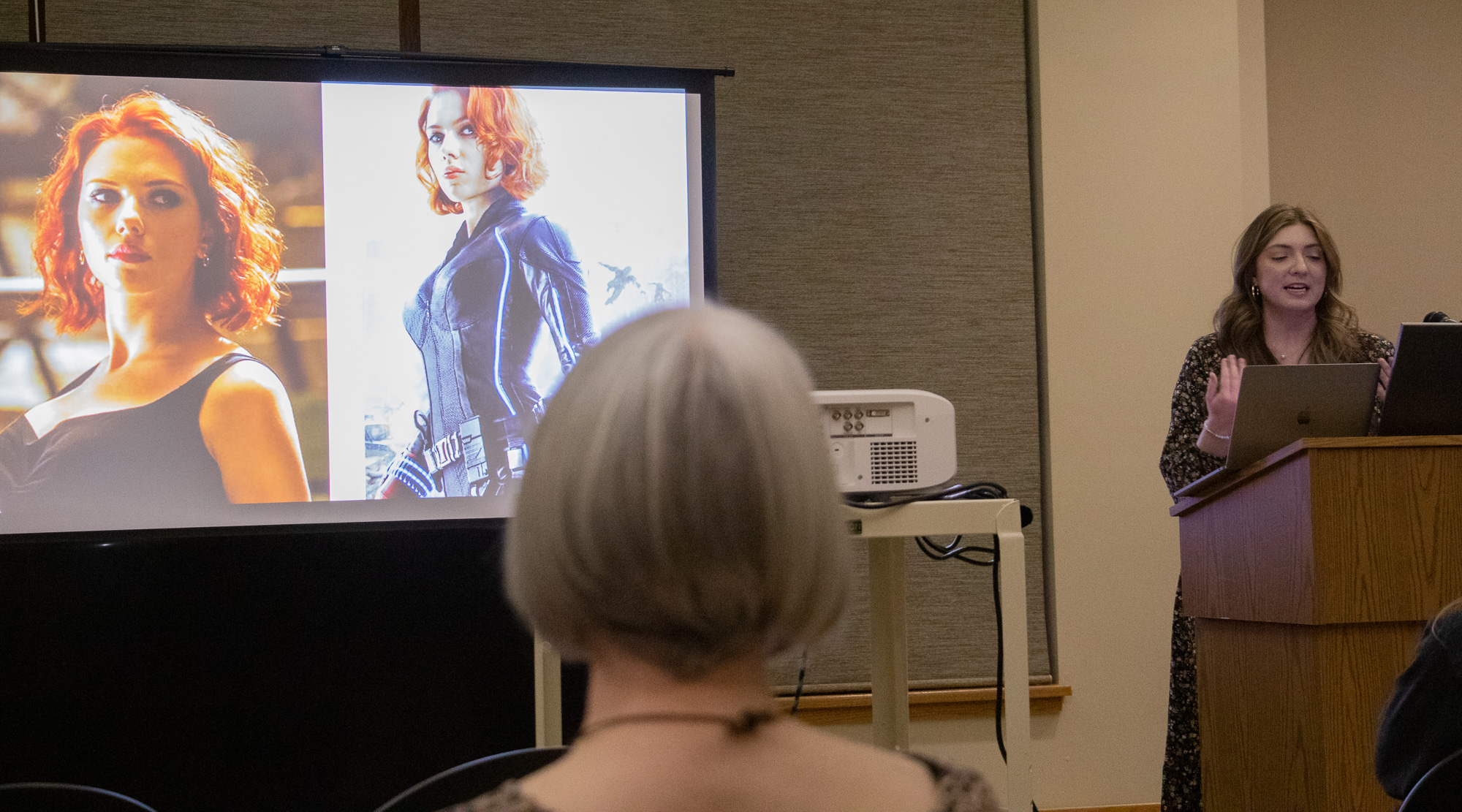 Woman with a slideshow speaking to an audience