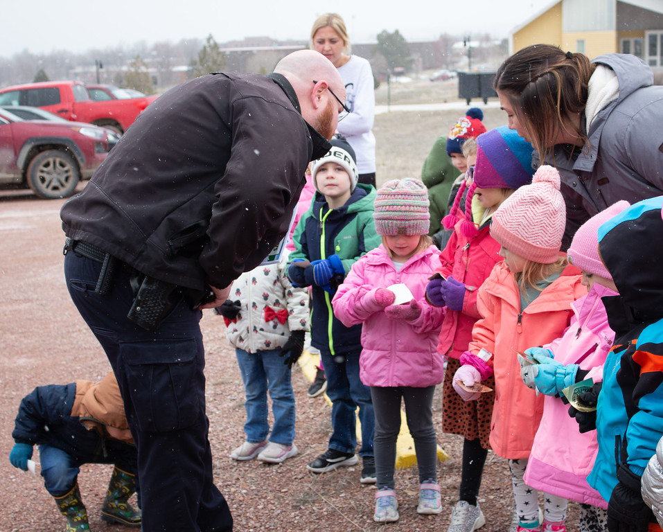 An officer greeting children and teachers outside