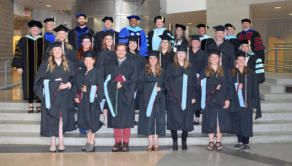 Group of graduates posing with college officials