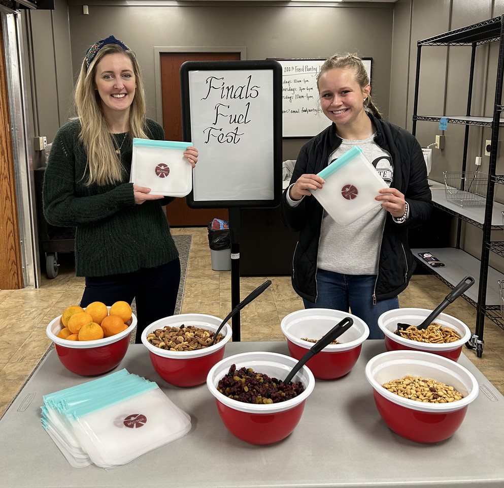 Two women standing by a table with food