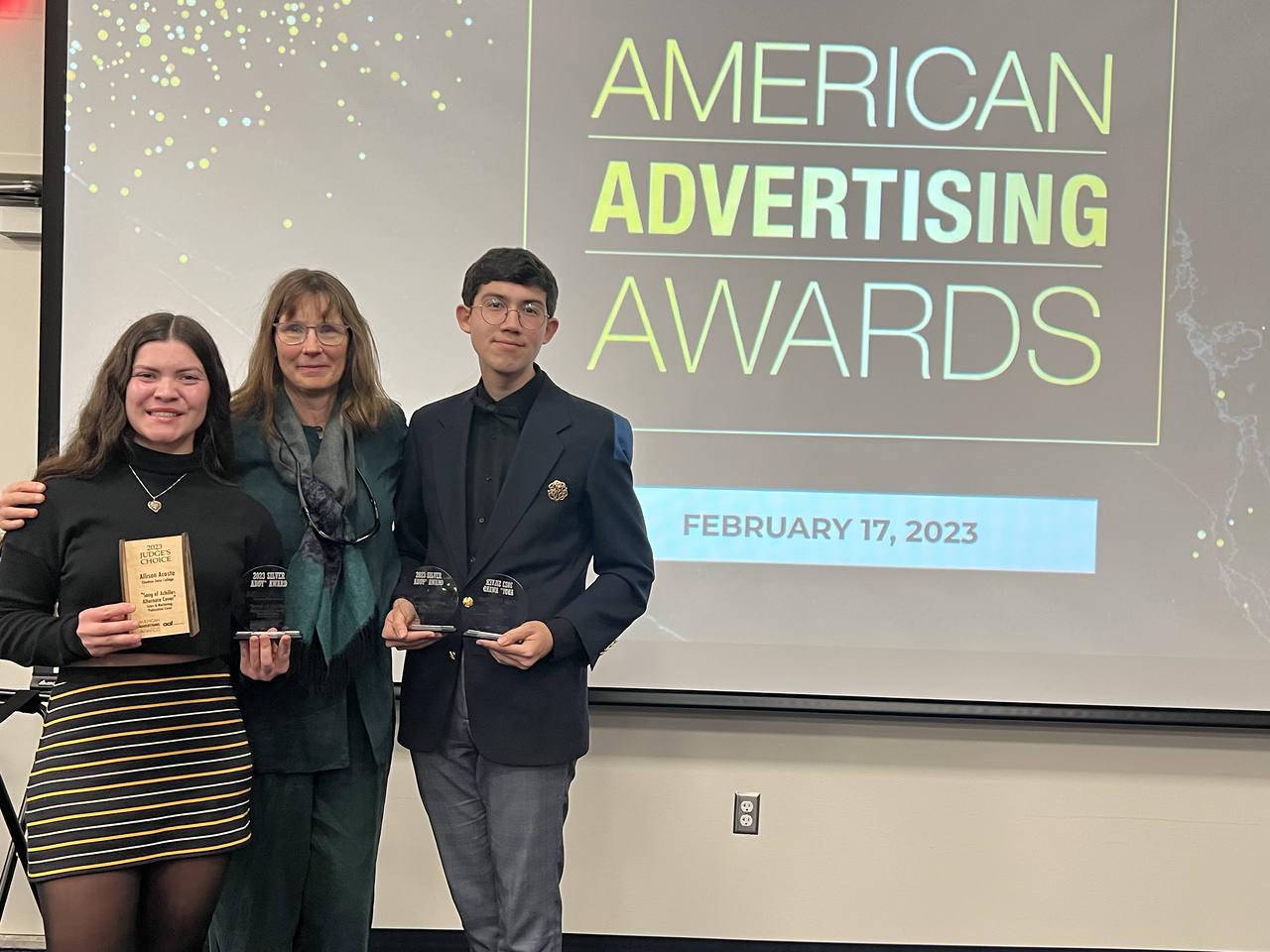 Three people standing at an awards ceremony