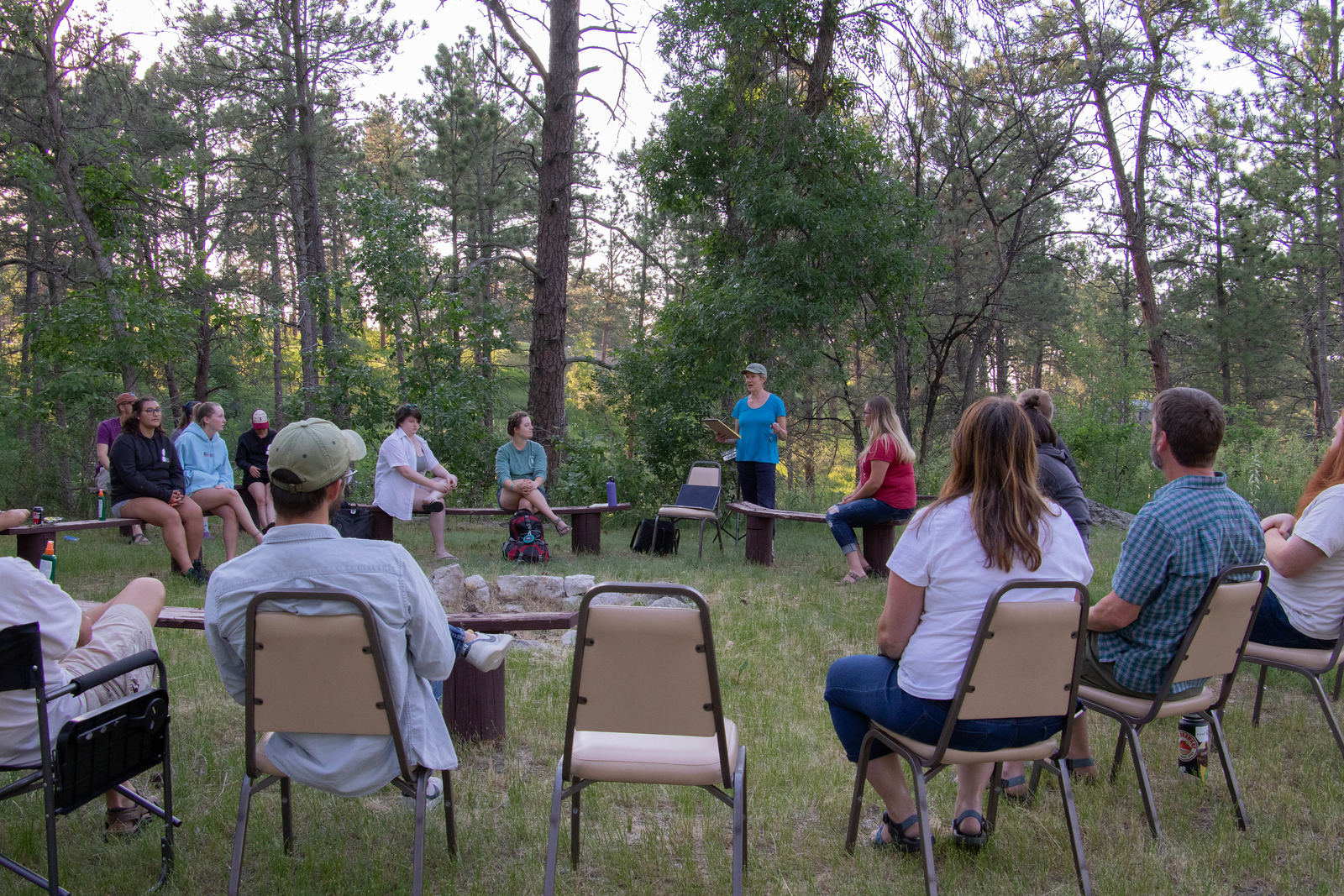 Woman standing outside reading to a circle of seated people