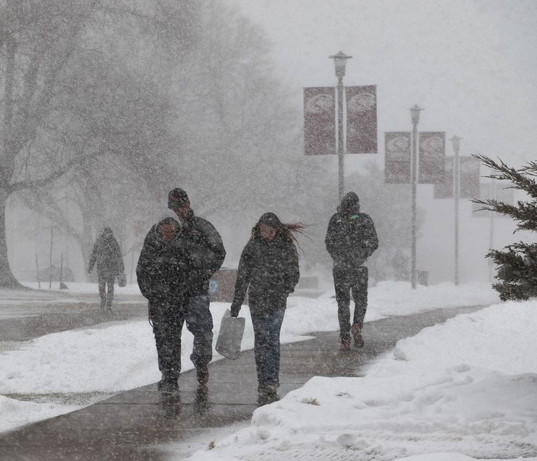 People walking on main campus sidewalk in snow