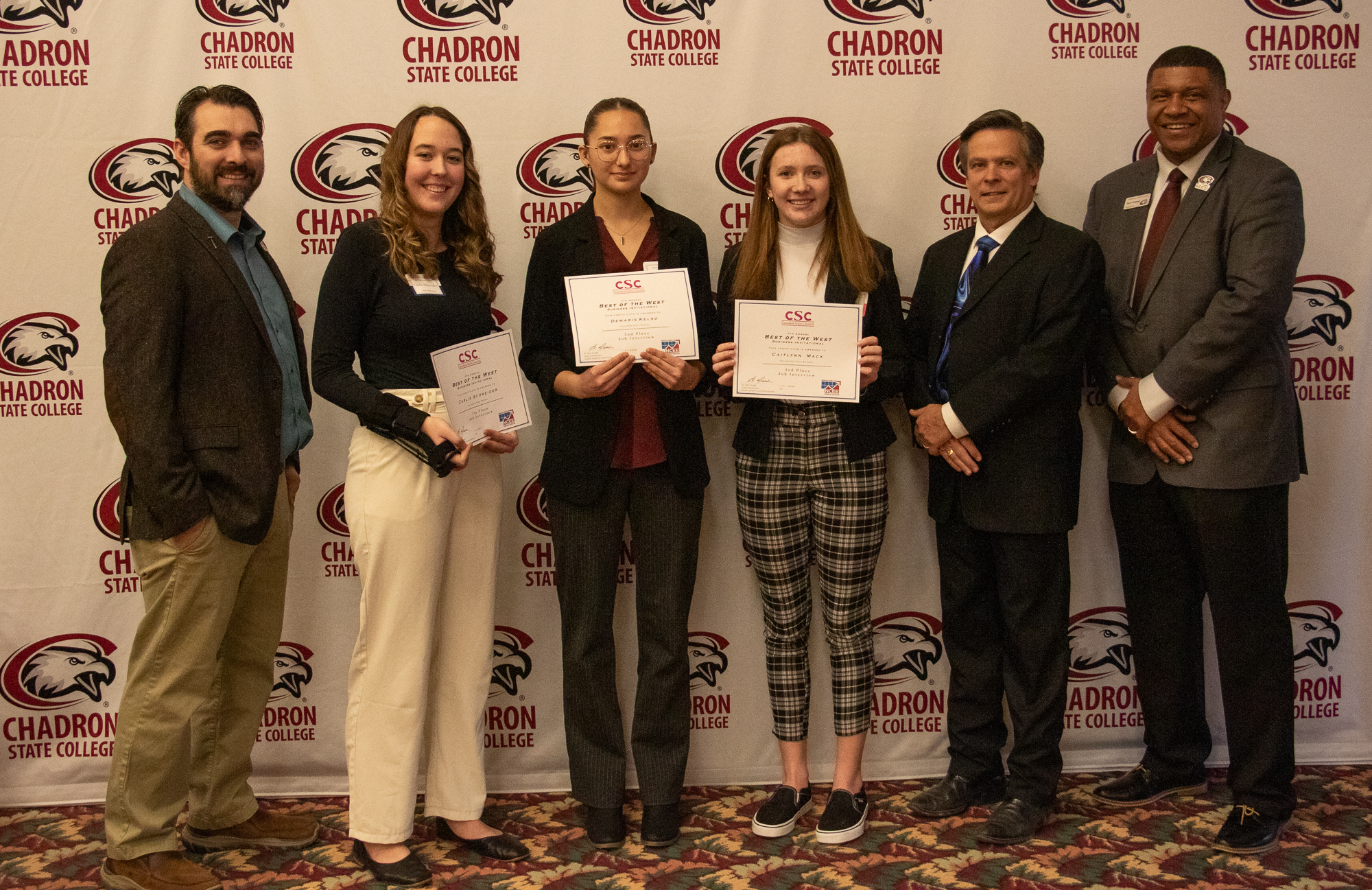 Six adults posing inside with awards